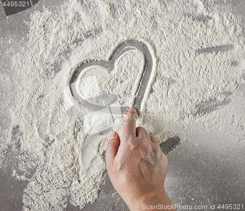 Image of cook hand drawing heart shape in flour