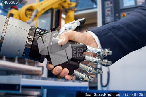 Image of Hand of a businessman shaking hands with a Android robot.