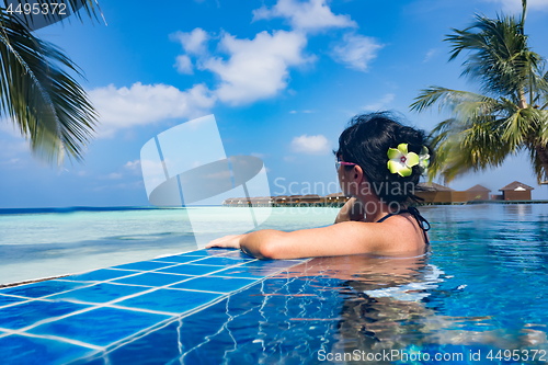 Image of Girl looking at the ocean while sitting by the pool