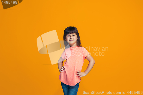 Image of The happy teen girl standing and smiling against orange background.