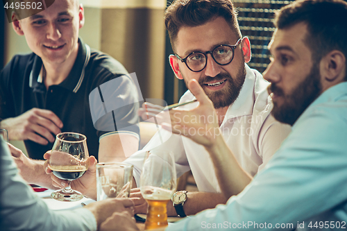 Image of Young cheerful people smile and gesture while relaxing in pub.