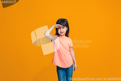 Image of The happy teen girl standing and smiling against orange background.