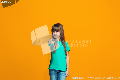 Image of The happy teen girl pointing to you, half length closeup portrait on orange background.