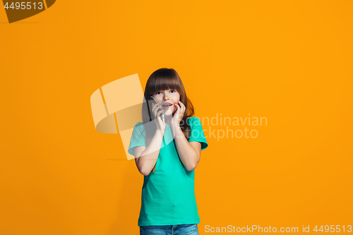 Image of The happy teen girl standing and smiling against orange background.