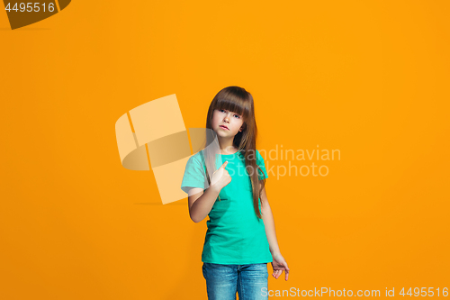 Image of Beautiful female half-length portrait on orange studio backgroud. The young emotional teen girl