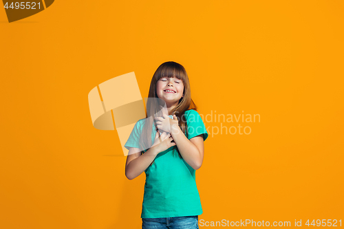 Image of The happy teen girl standing and smiling against orange background.