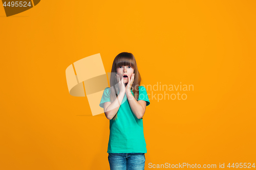 Image of Beautiful teen girl looking suprised isolated on orange