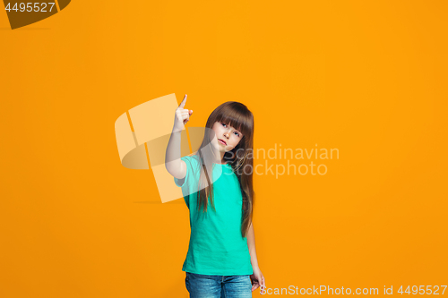 Image of Beautiful female half-length portrait on orange studio backgroud. The young emotional teen girl