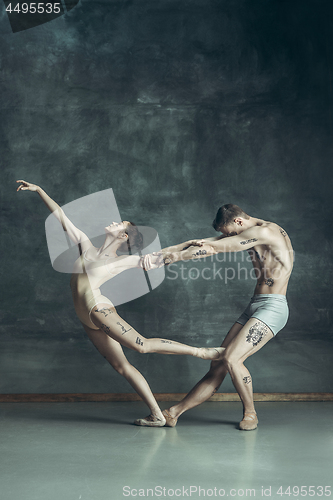 Image of The young modern ballet dancers posing on gray studio background