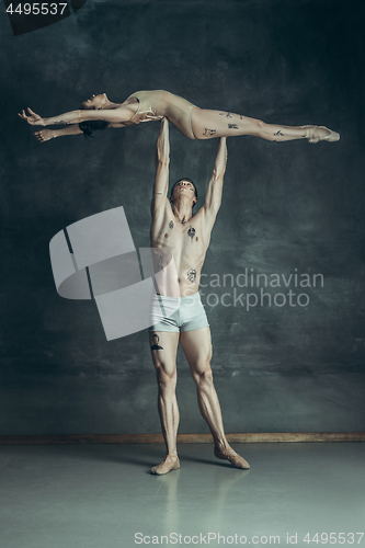 Image of The young modern ballet dancers posing on gray studio background