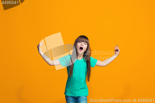 Image of Beautiful female half-length portrait on orange studio backgroud. The young emotional teen girl