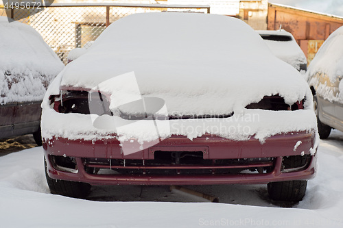 Image of Front of abandoned car covered with snow.