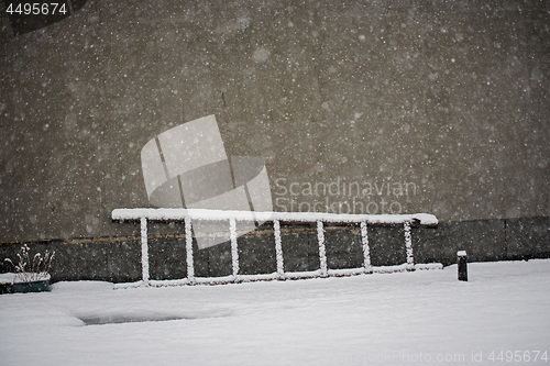 Image of Old wooden ladder laying on the snow near the wall