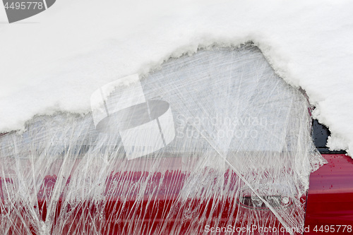 Image of Front window of abandoned car wrapped in plastic and covered with snow.