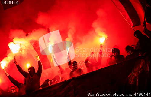 Image of football hooligans with mask holding torches in fire