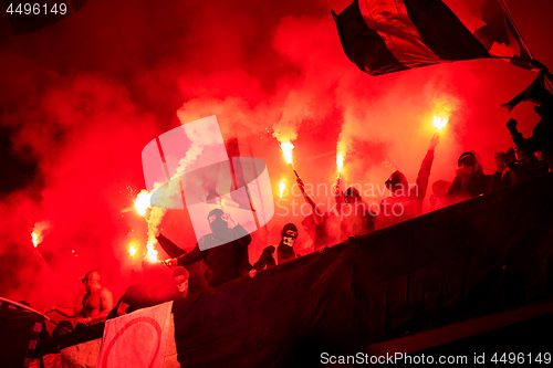 Image of football hooligans with mask holding torches in fire