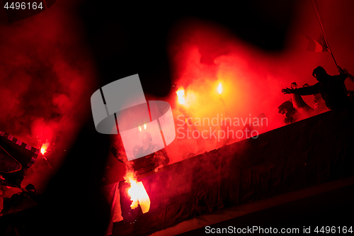 Image of football hooligans with mask holding torches in fire