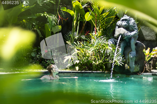 Image of Sensual young woman relaxing in outdoor spa infinity swimming pool surrounded with lush tropical greenery of Ubud, Bali.