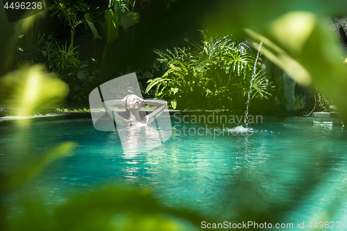 Image of Sensual young woman relaxing in outdoor spa infinity swimming pool surrounded with lush tropical greenery of Ubud, Bali.