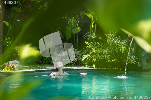 Image of Sensual young woman relaxing in outdoor spa infinity swimming pool surrounded with lush tropical greenery of Ubud, Bali.