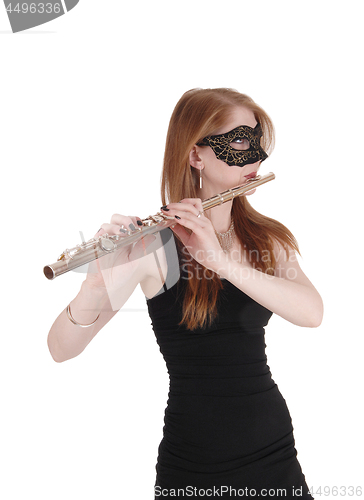 Image of Woman standing and playing the flute with a mask