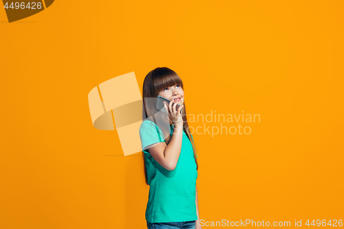 Image of The happy teen girl standing and smiling against orange background.