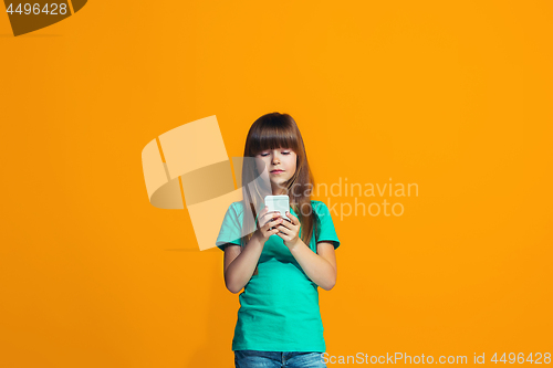 Image of The happy teen girl standing and smiling against orange background.