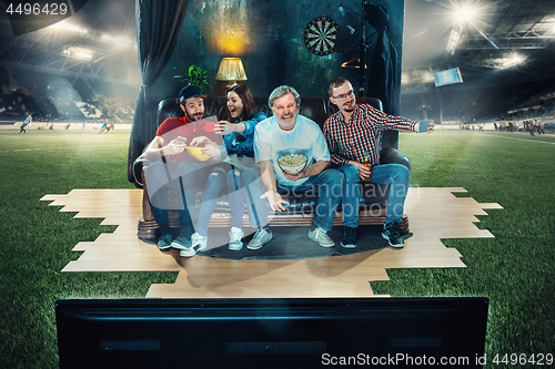 Image of Soccer football fans sitting on the sofa and watching TV in the 