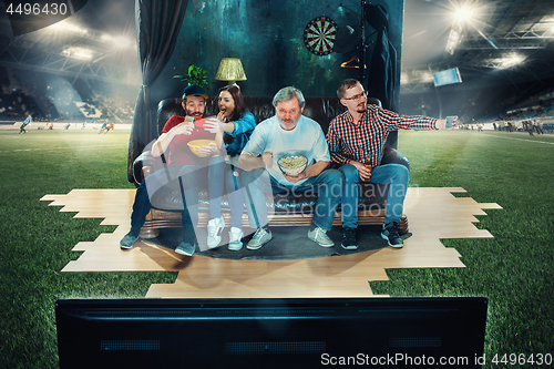 Image of Soccer football fans sitting on the sofa and watching TV in the 