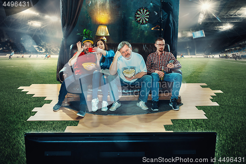 Image of Soccer football fans sitting on the sofa and watching TV in the 