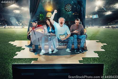 Image of Soccer football fans sitting on the sofa and watching TV in the 