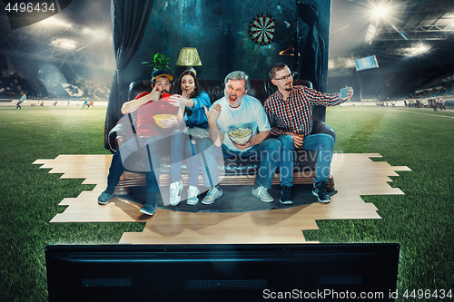 Image of Soccer football fans sitting on the sofa and watching TV in the 