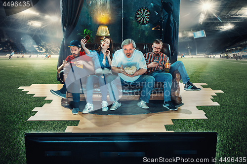 Image of Soccer football fans sitting on the sofa and watching TV in the 