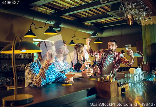 Image of Sport, people, leisure, friendship and entertainment concept - happy football fans or male friends drinking beer and celebrating victory at bar or pub