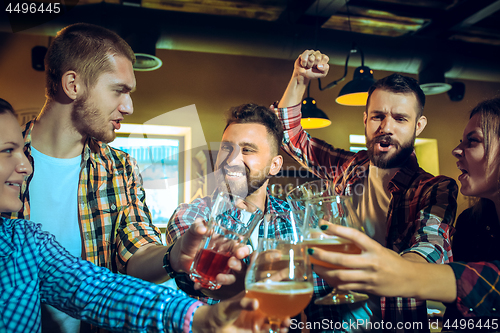 Image of Sport, people, leisure, friendship and entertainment concept - happy football fans or male friends drinking beer and celebrating victory at bar or pub