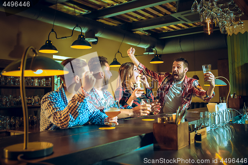 Image of Sport, people, leisure, friendship and entertainment concept - happy football fans or male friends drinking beer and celebrating victory at bar or pub