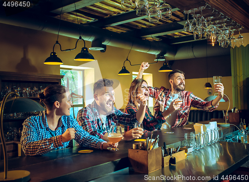 Image of Sport, people, leisure, friendship and entertainment concept - happy football fans or male friends drinking beer and celebrating victory at bar or pub