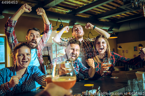 Image of Sport, people, leisure, friendship and entertainment concept - happy football fans or male friends drinking beer and celebrating victory at bar or pub