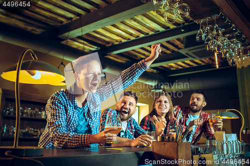 Image of Sport, people, leisure, friendship and entertainment concept - happy football fans or male friends drinking beer and celebrating victory at bar or pub