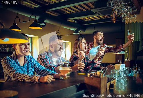 Image of Sport, people, leisure, friendship and entertainment concept - happy football fans or male friends drinking beer and celebrating victory at bar or pub