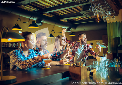 Image of Sport, people, leisure, friendship and entertainment concept - happy football fans or male friends drinking beer and celebrating victory at bar or pub