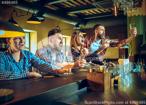 Image of Sport, people, leisure, friendship and entertainment concept - happy football fans or male friends drinking beer and celebrating victory at bar or pub