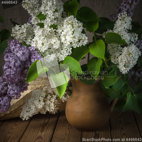 Image of Still-life with a bouquet of lilacs and a straw hat