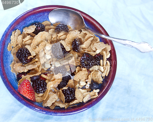 Image of raisin bran breakfast cereal with blackberries blueberries straw