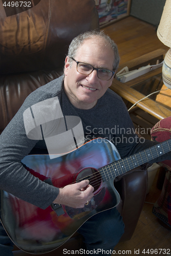 Image of middle age senior man playing acoustic guitar