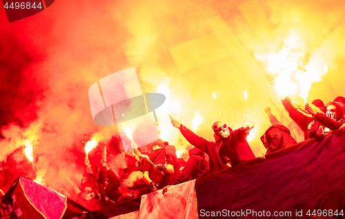 Image of football hooligans with mask holding torches in fire