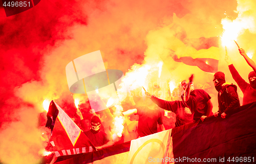 Image of football hooligans with mask holding torches in fire