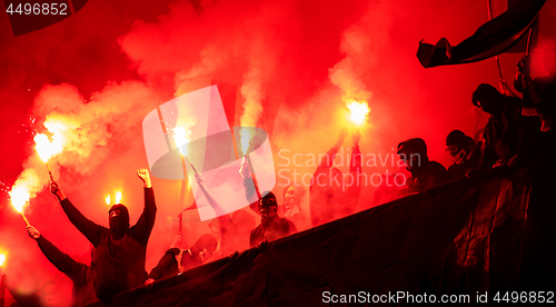 Image of football hooligans with mask holding torches in fire