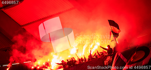 Image of football hooligans with mask holding torches in fire