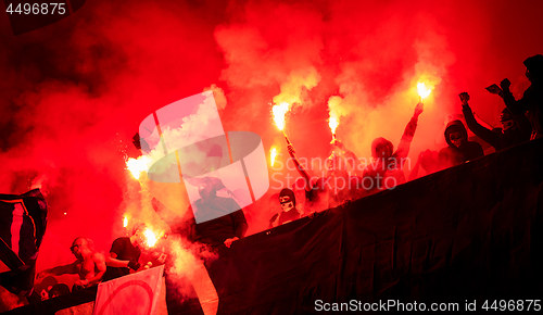 Image of football hooligans with mask holding torches in fire